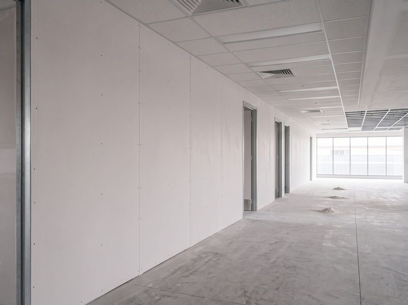 Commercial partition wall sheeted and fixed, sheet joints and straight screw lines visible, ready for setting beneath a suspended ceiling