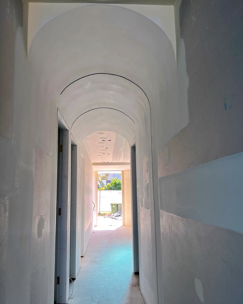 The same hallway with the barrel vault sanded smooth and light running the full length of the arch, ready for the painter