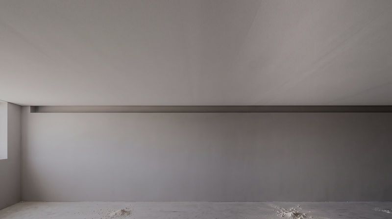 Recessed shadow line detail where a plasterboard ceiling meets the wall, picked out by low raking light