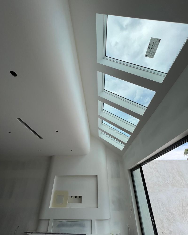 Faceted plaster forms folding around an angled skylight run in a double height void, set and finished