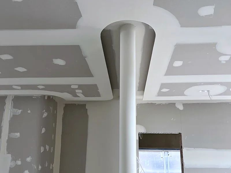 Flared plaster capital formed where a round column meets a stepped ceiling, joints set and awaiting sanding