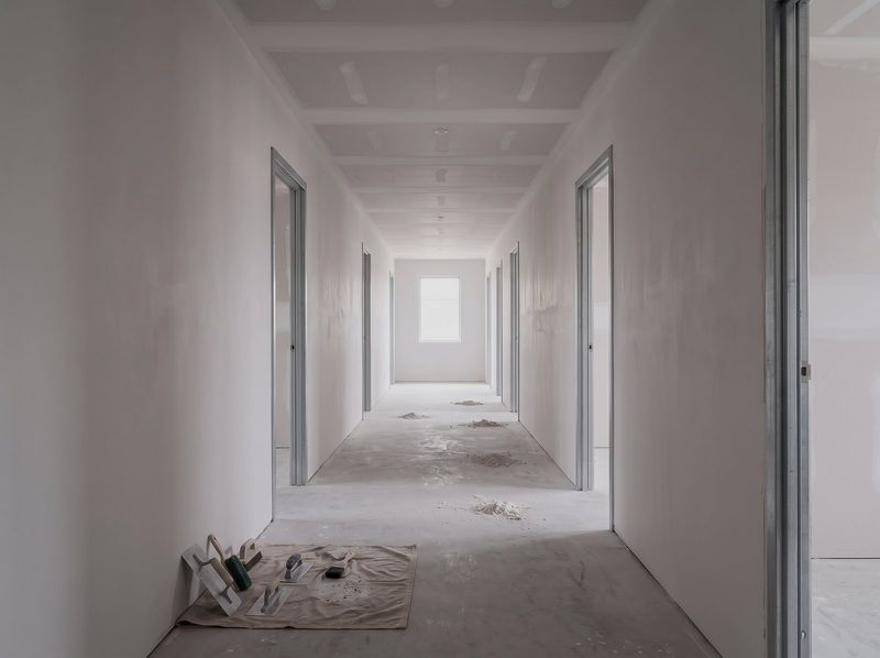 Fitout corridor with plasterboard walls and ceiling set and sanded, steel door frames either side and light at the far end