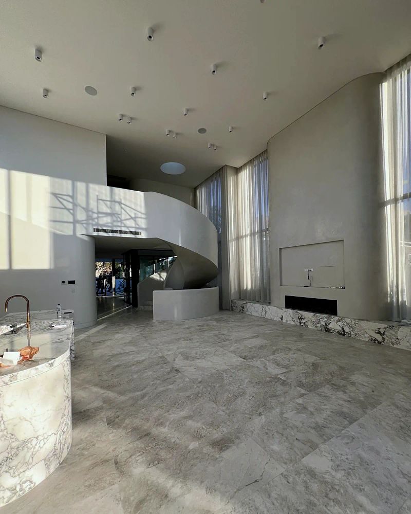 Double height living space with a sculptural curved plaster stair and set walls running the full height