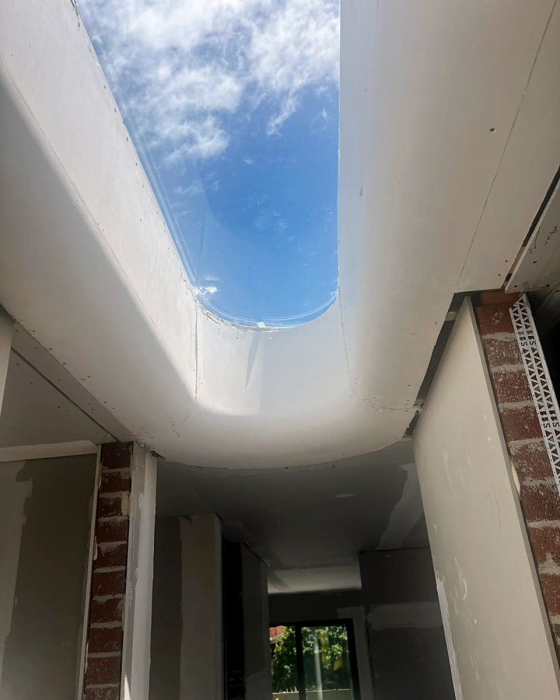Curved plaster reveal formed around a long skylight opening, the board set and taped ready for finishing